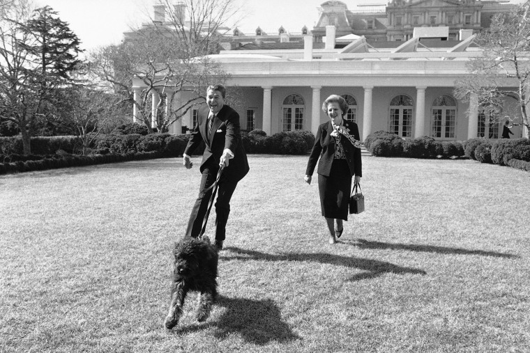 President Ronald Reagan is pulled along by his pet dog Lucky while he and British Prime Minister Margaret Thatcher take a stroll in the White House Rose Garden on Feb. 20, 1985 in Washington, D.C. (Photo by Barry Thumma/AP)