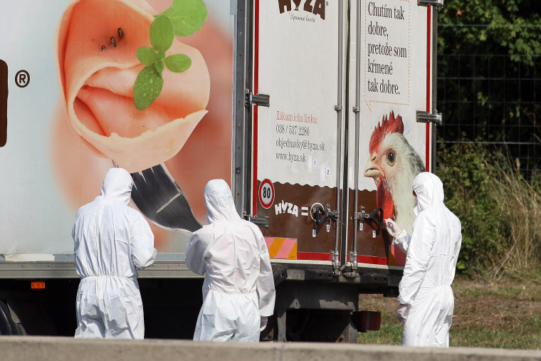 Investigators stand near a truck that stands on the shoulder of the highway A4 near Parndorf south of Vienna, Austria on Aug. 27, 2015. (Photo by Ronald Zak/AP)