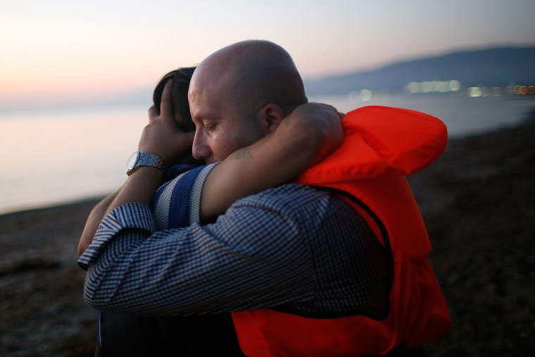 Members of a migrant family from Syria embrace each other after completing a three mile crossing of the Aegean Sea to the island of Kos from Turkey August 28, 2015 in Kos, Greece. (Photo by Win McNamee/Getty)
