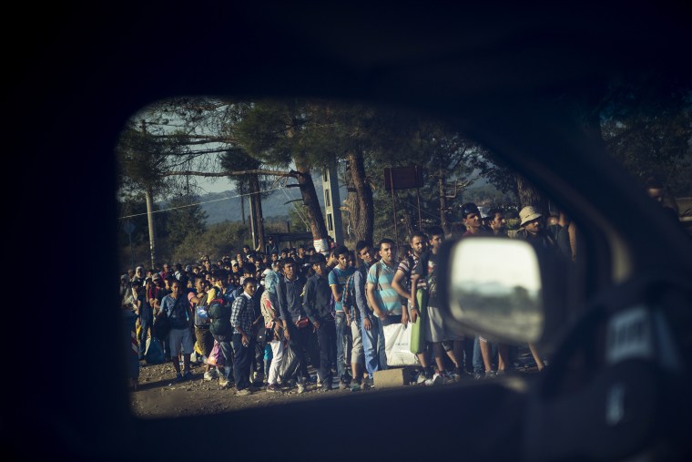 Migrants are seen through the window of a police car at the Greek-Macedonian border, as they wait to be allowed by Macedonian police to cross the border, Idomeni, northern Greece, Aug. 27, 2015. (Photo by Santi Palacios/AP)