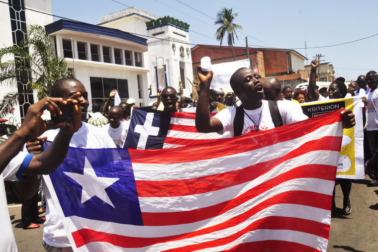 People march with a Liberian flag as they celebrate Liberia being an Ebola free nation in Monrovia, Liberia, Monday, May 11, 2015. (Photo by Abbas Dulleh/AP)