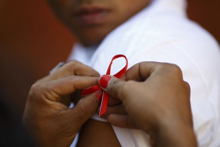 A red ribbon is put on the sleeves of a man by his friend to show support for people living with HIV during a program to raise awareness about AIDS on World AIDS Day in Kathmandu on Dec. 1, 2013. (Photo by Navesh Chitrakar/Reuters)