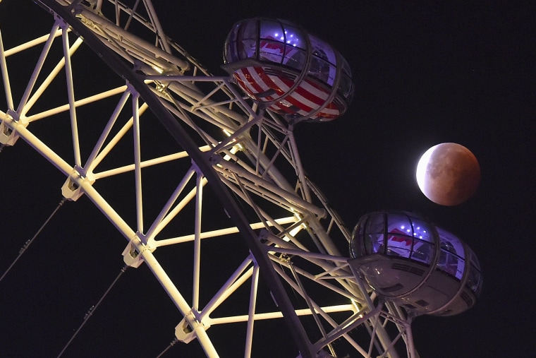 A supermoon is seen during a lunar eclipse behind pods of the London Eye wheel in London, on Sept. 28, 2015. (Photo by Toby Melville/Reuters)