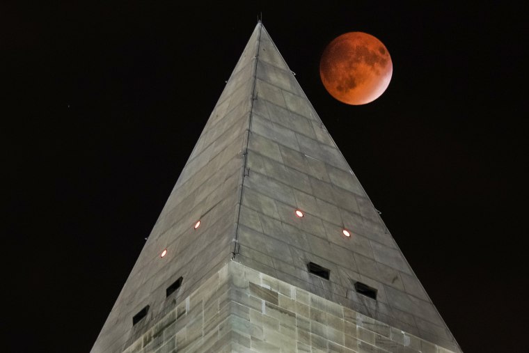 The so-called supermoon passes behind the peak of the Washington Monument during a lunar eclipse, Sept. 27, 2015 in Washington, D.C. (Photo by J. David Ake/AP)