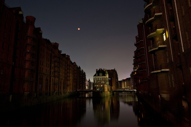 The perigee full moon, or supermoon, appears red on the night sky above the 'Speicherstadt' in Hamburg, Germany, Sept. 28, 2015. (Photo by Christian Charisius/DPA/AP)
