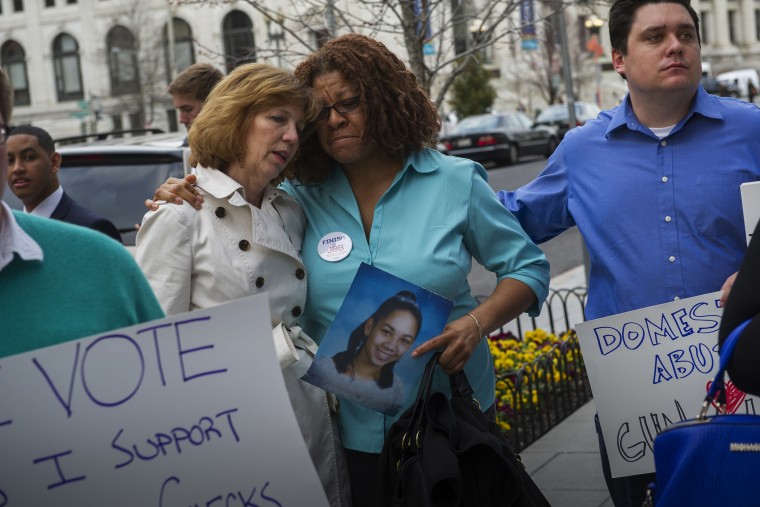 Relatives of victims of notable shootings comfort one another during a protest outside the National Shooting Sports Foundation's annual Congressional Fly-In fundraising dinner April 2, 2014, in Washington, DC. (Photo by Rod Lamkey/Getty)
