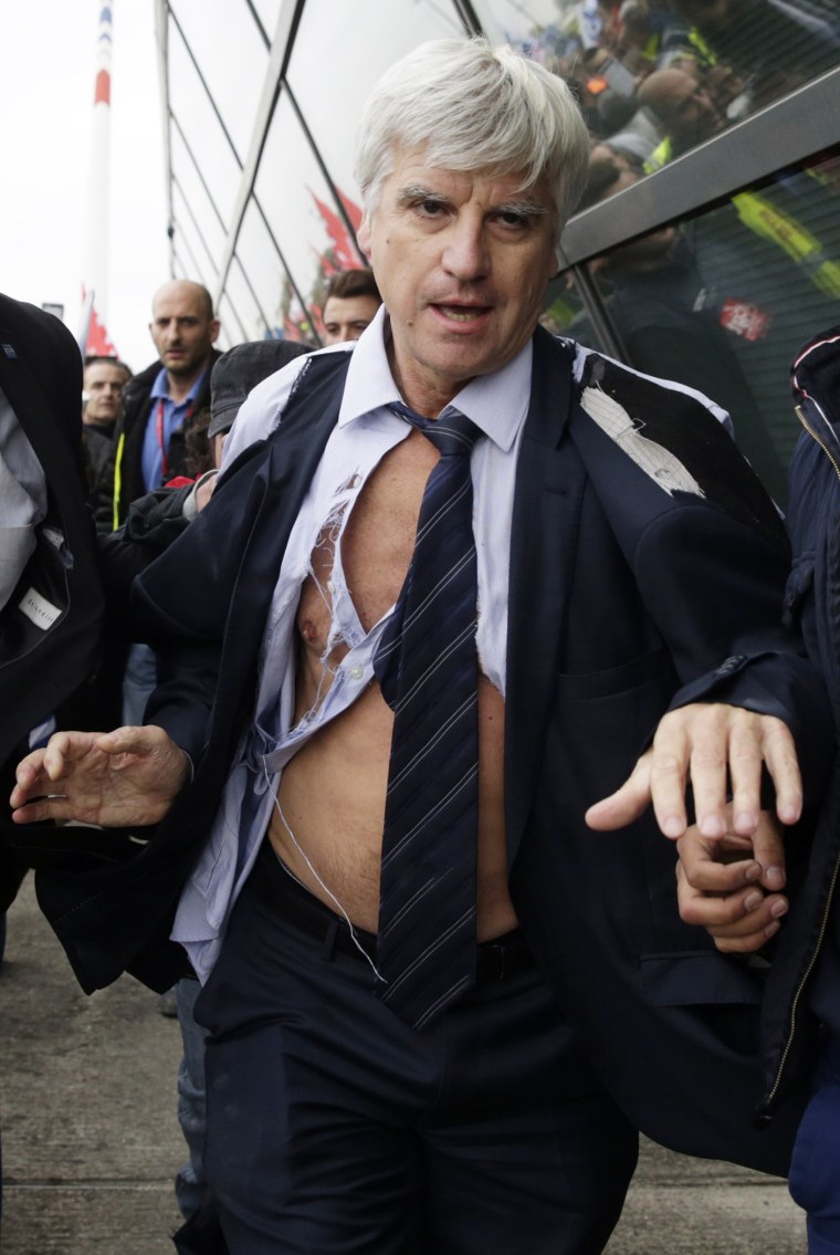 Air France's director of long-haul flights, Pierre Plissonnier, nearly shirtless, is led away from demonstrators by security officers in Roissy-en-France, on Oct. 5, 2015. (Photo by Kenzo Tribouillard/AFP/Getty)