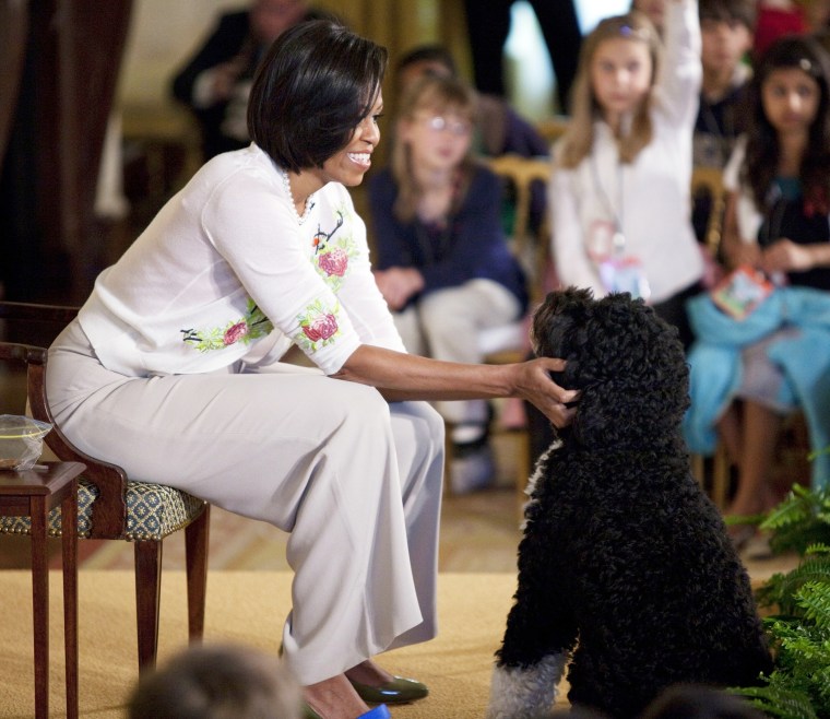 First lady Michelle Obama pets the family dog Bo during an event to welcome children of Executive Office employees at the White House's annual take our daughters and sons to work day on April 22, 2010 in Washington, D.C. (Photo by Evan Vucci/AP)