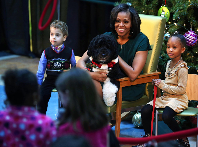 First lady Michelle Obama talks to children as her dog Bo sits on her lap and 5-year-old AJ Murray (L), and 5-year-old Jordyn Akyoko sit nearby at Children's National Medical Center on Dec. 14, 2012 in Washington, D.C. (Photo by Mark Wilson/Getty)