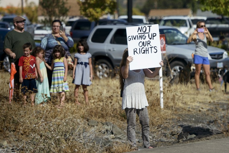 Demonstrators watch as a motorcade with US President Barack Obama passes on Oct. 9, 2015 in Roseburg, Ore. (Photo by Brendan Smialowski/AFP/Getty)