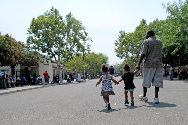 A man walks with two children outside the Poverello House homeless shelter Thursday, July 31, 2014, in Fresno, Calif. (Photo by Scott Smith/AP)