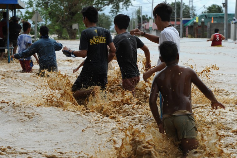 Residents brave a strong flood current along a submerged highway in Santa Rosa town, Nueva Ecija province, north of Manila on Oct. 19, 2015, a day after typhoon Koppu hit Aurora province. (Photo by Ted Aljibe/AFP/Getty)