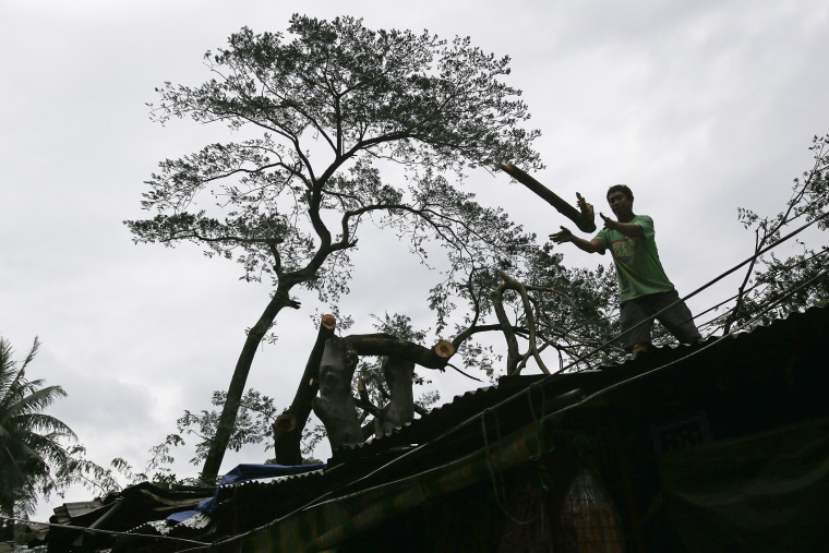 A worker removes sections of a fallen tree from a damaged house caused by Typhoon Koppu in suburban Quezon city, north of Manila, Philippines on Oct. 19, 2015. (Photo by Aaron Favila/AP)