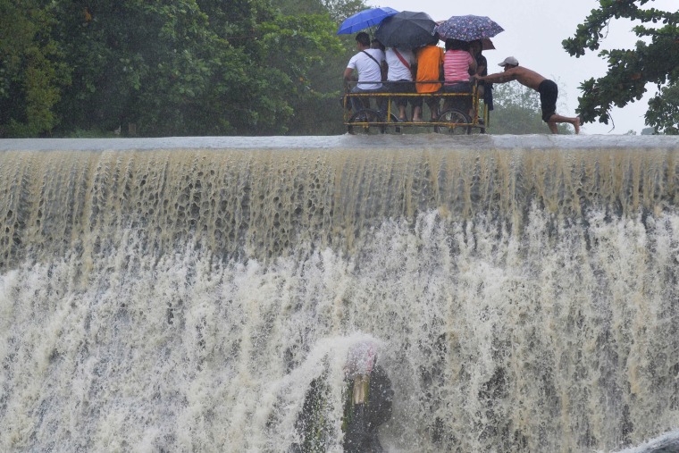 Residents cross a swelling dam, due to rising waters brought about by Typhoon Koppu, in Las Pinas city, metro Manila on Oct. 19, 2015. (Photo by Ezra Acayan/Reuters)