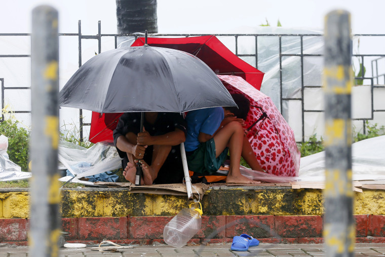 Residents huddle together under their umbrellas as strong winds and slight rain are brought by Typhoon Koppu Oct. 18, 2015 in Manila, Philippines. (Photo by Bullit Marquez/AP)