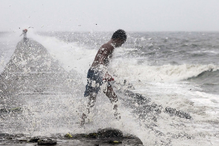 A boy searches for reusable plastic bottles while being pelted by waves brought by typhoon Koppu in Manila Bay Oct. 18, 2015. (Photo by Romeo Ranoco/Reuters)