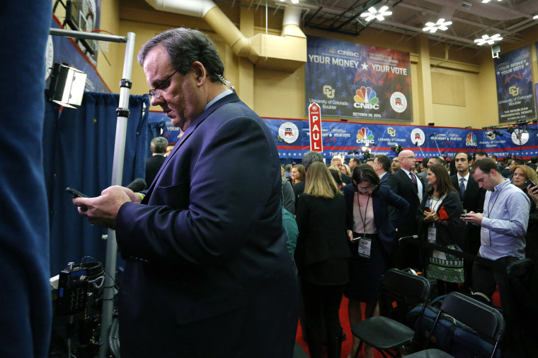 Chris Christie, left, checks his phone in the spin room following the CNBC Republican presidential debate at the University of Colorado, Oct. 28, 2015, in Boulder, Colo. (Photo by Brennan Linsley/AP)