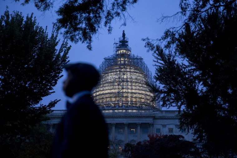 The U.S. Capitol building surrounded by scaffolding as someone walks by on Oct. 28, 2015, in Washington, D.C. (Photo by Andrew Harrer/Bloomberg/Getty)