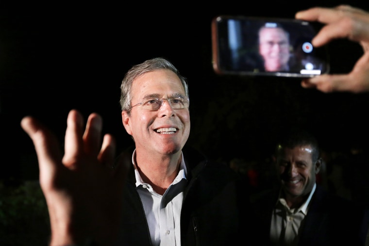 In this Nov. 3, 2015, photo Republican presidential candidate, former Florida Gov. Jeb Bush is recorded as he speaks into a mobile phone while departing a campaign event in Rye, N.H. (Photo by Steven Senne/AP)