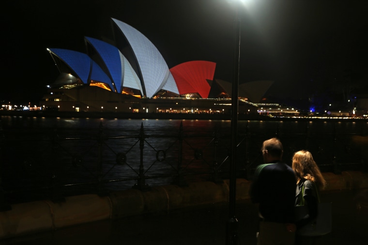 A couple look at the sails of the Sydney Opera House that are lit in the colors of the French flag in Sydney, Nov. 14, 2015, following the terrorist attacks in Paris. (Photo by Rick Rycroft/AP)