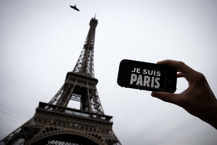 A person holds aloft a smartphone bearing the message \"Je Suis Paris\" in front of the Eiffel Tour, following a series of attacks on the city in which at least 128 people were killed. (Photo by Joel Saget/AFP/Getty)