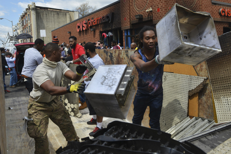 Neighbors and volunteers work to clean up a CVS store that was looted and burned during clashes with protesters and police the night before in Baltimore, Md., April 28, 2015. (Photo by Jay Mallin/ZUMA Wire)