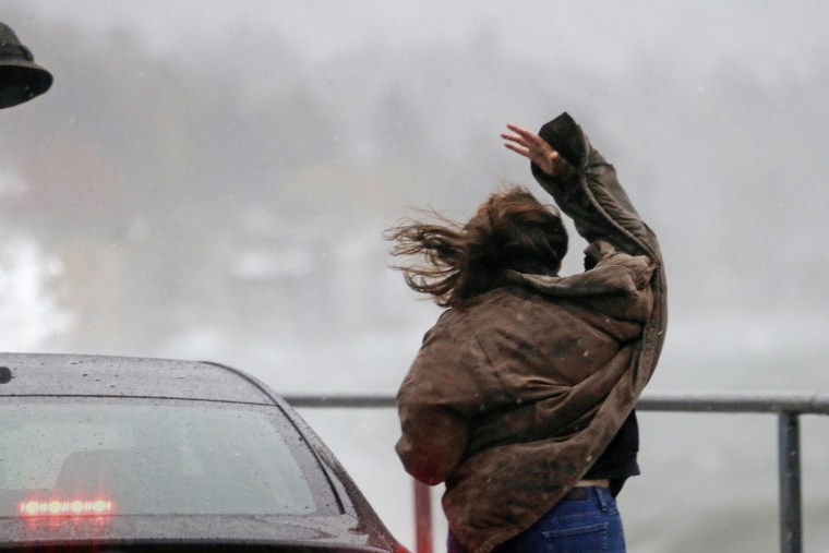 A woman loses her hat to the wind as she steps out of her car to look at high waves, Nov. 17, 2015, in the West Seattle neighborhood of Seattle. (Photo by Elaine Thompson/AP)
