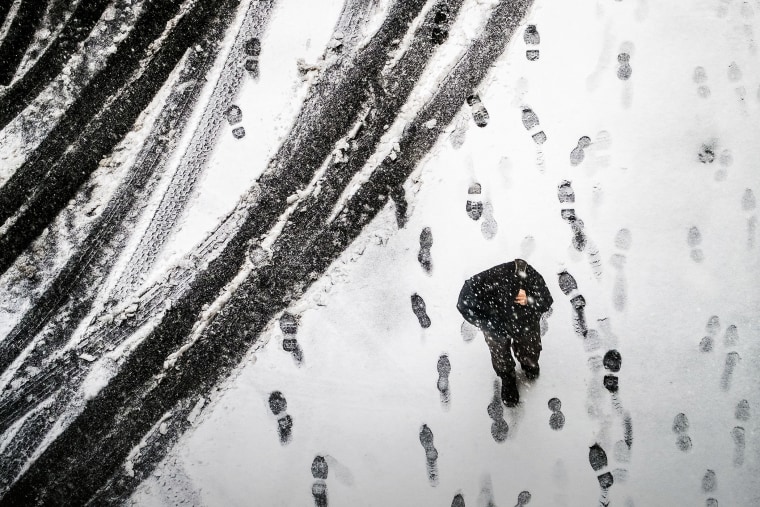 A pedestrian walks through an alley in downtown Washington, March 5, 2015, as snow begins to accumulate. (Photo by J. David Ake/AP)