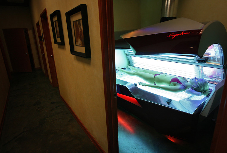 Erika Greet, an employee of U-Tan, a tanning salon located near USC, demonstrates for a photographer the workings of an Ergoline Excellence tanning bed. (Photo by Robert Gauthier/Los Angeles Times/Getty)
