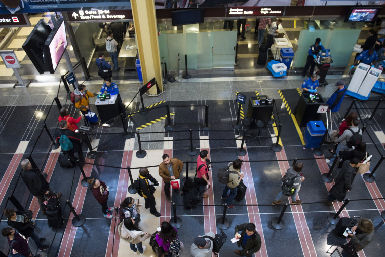 Passengers stand in line to go through a TSA security checkpoint as they head to their flights at Reagan National Airport in Arlington, Va., Dec. 23, 2015. (Photo by Saul Loeb/AFP/Getty)