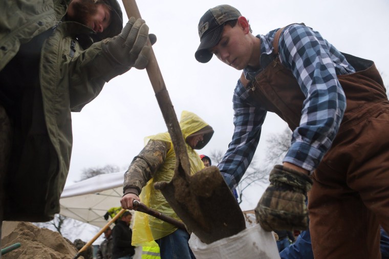 Jesse Nelson, 32, of Barnhart, Mo., and Ryan Morris, 20, of Imperial, join other volunteers in making sandbags as the Mississippi River rises after several days of rain in Kimmswick, Dec. 27, 2015. (Photo by Cristina M. Fletes/St. Louis Post-Dispatch/AP)