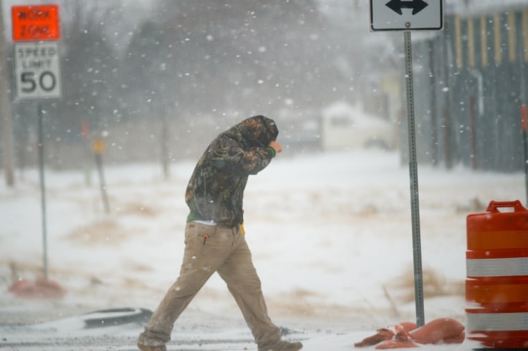 A highway worker tries to shield himself while walking to his truck on Dec. 27, 2015 in Lubbock, Texas. Coming on the heels of several strong tornadoes, some northern parts of Texas are experiencing blizzard conditions. (Photo by John Weast/Getty)