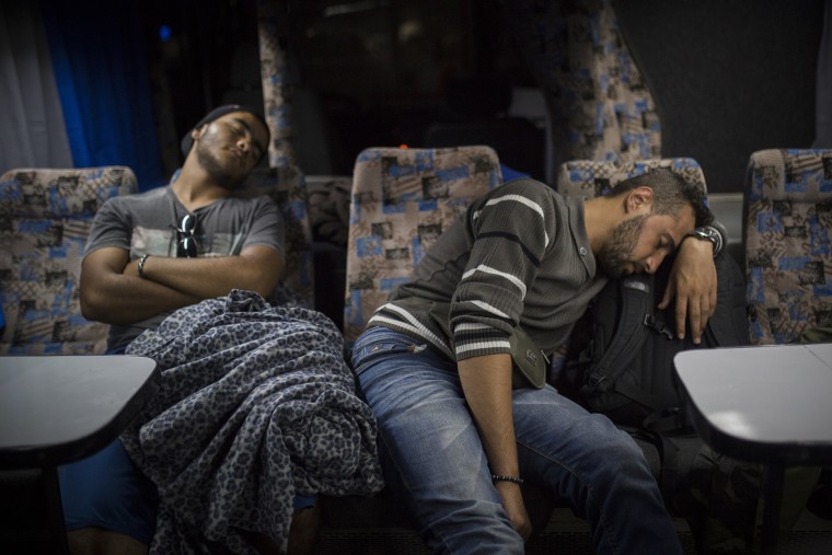 Mohammed al-Haj, right, and his friend Abdul-Rahman Babelly sleep on a bus traveling from Presevo, in southern Serbia, to the capital, Belgrade, their next stop en route to the Hungarian bordery, Sep. 12, 2015. (Photo by Santi Palacios/AP)