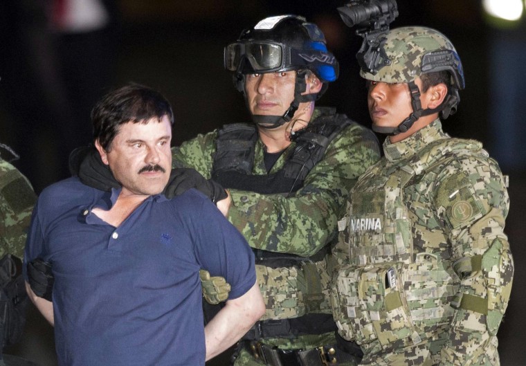 In this Friday, Jan. 8, 2016 photo, Joaquin \"El Chapo\" Guzman is made to face the press as he's escorted to a helicopter in handcuffs by soldiers and marines at a federal hangar in Mexico City. (Photo by Eduardo Verdugo/AP)