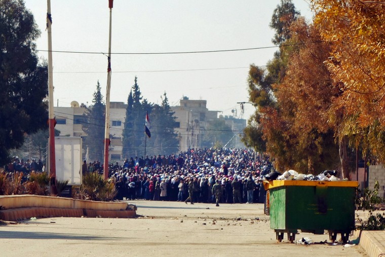 A handout photo dated Feb. 3, 2016 shows a crowd of people waiting on the edge of a buffer zone that was created in preparation for a food aid distribution in the besieged town of Moadamiyeh, Syria. (Photo by Pawel Krysiek/Handout/EPA)