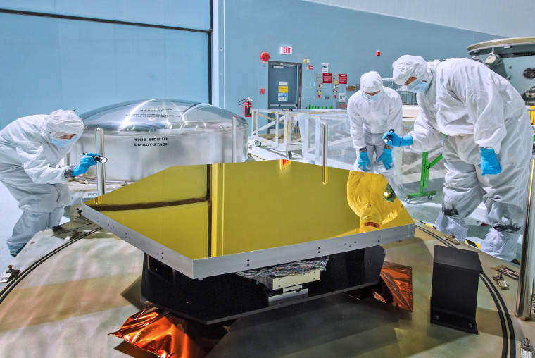 Technicians and scientists check out one of the Webb telescope's first two flight mirrors in the clean room at NASA's Goddard Space Flight Center in Greenbelt, MD.