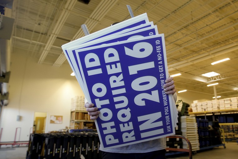 A worker carries signs about a voter ID law that went into effect in 2016 at the Mecklenburg County Board of Elections warehouse in Charlotte, N.C., Nov. 3, 2014. (Photo by Chris Keane/Reuters/Corbis)