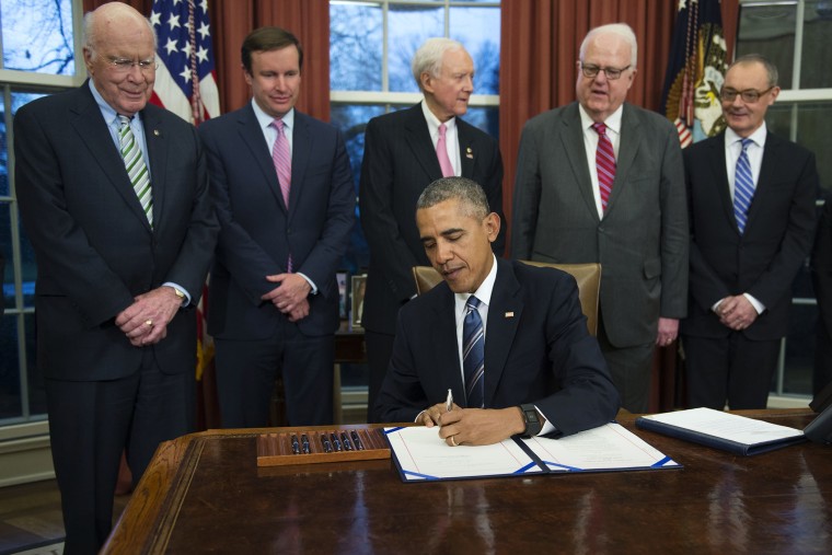 President Barack Obama, flanked by lawmakers and supporters of the bill, signs H.R. 1428 during a ceremony in the Oval Office of the White House on Feb. 24, 2016 in Washington, DC. (Photo by Shawn Thew/Pool/Getty)