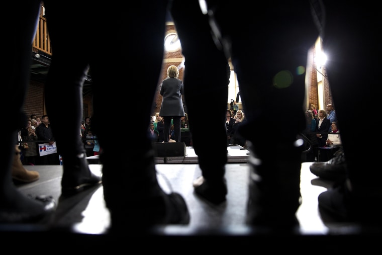 Seen through the legs of attendees, Hillary Clinton, a Democratic presidential hopeful, speaks during a campaign event at the Lyman and Merrie Wood Museum of Springfield History in Springfield, Mass.