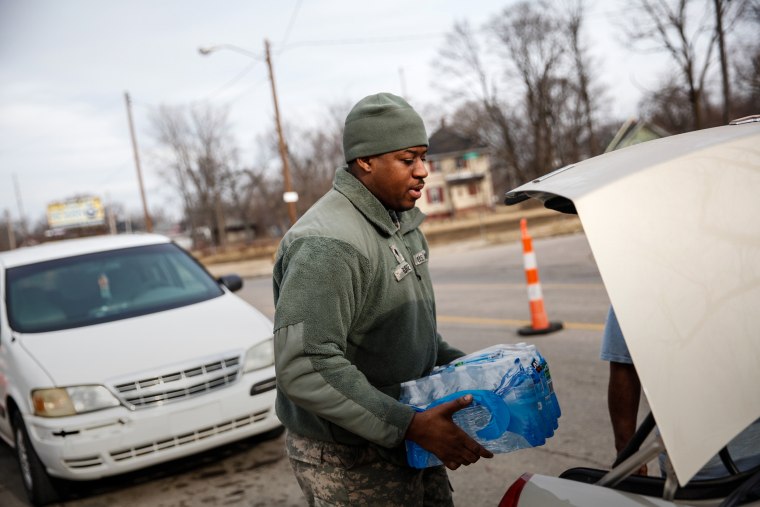 Army National Guard Spc. Terence Burse carries bottled water out to the car for a resident on Feb. 7, 2016 in Flint, Mich. (Photo by Sarah Rice/Getty)
