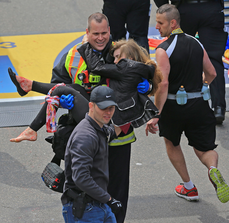 Emergency personnel respond to the scene after two explosions went off near the finish line of the 117th Boston Marathon on April 15, 2013. Victim Victoria McGrath is helped to a stretcher. (Photo by David L. Ryan/The Boston Globe/Getty)