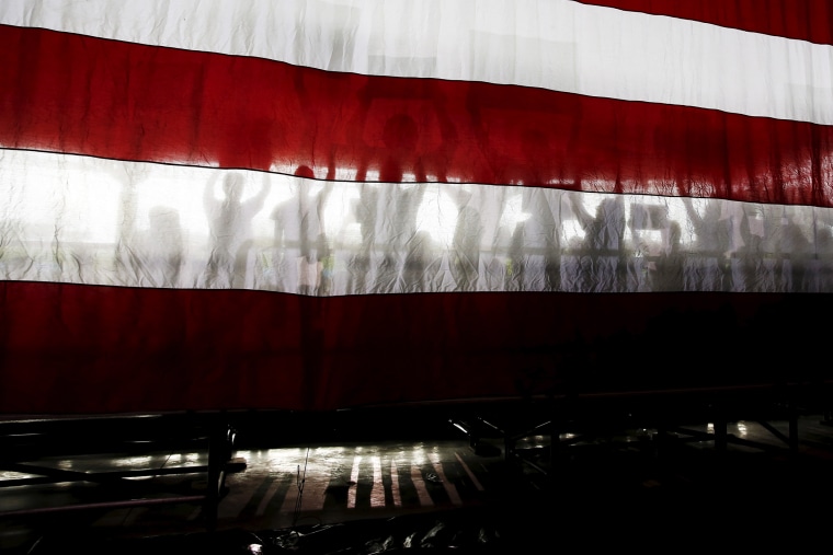 Supporters of Democratic presidential candidate Bernie Sanders are seen in silhouette behind the U.S. flag during a rally in Charlotte, N.C., March 14, 2016. (Photo by Shannon Stapleton/Reuters)