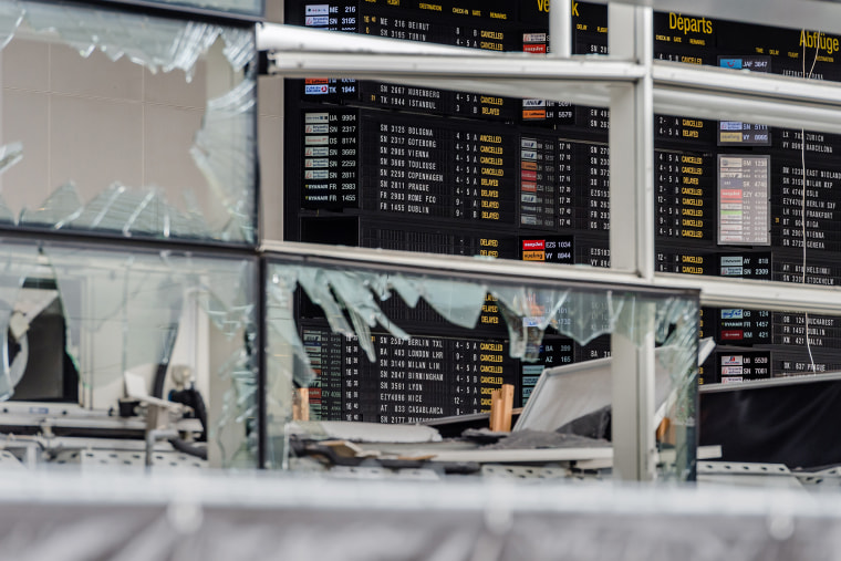 An arrivals and departure board is seen behind blown out windows at Zaventem Airport in Brussels on March 23, 2016. (Photo by Geert Vanden Wijngaert/AP)