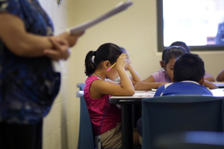 Elementary aged children talk about a short story in Spanish during a class at the Karnes County Residential Center, a temporary home for immigrant women and children detained at the border in Karnes City, Texas on Sept. 10, 2014. (Photo by Eric Gay/AP)