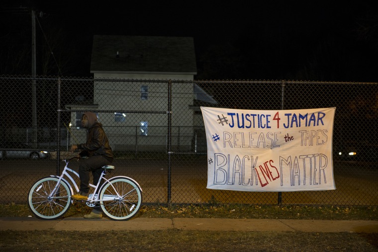 A man pauses on his bike while passing through the protests outside the 4th Precinct police station November 20, 2015 in Minneapolis, Minn. (Photo by Stephen Maturen/Getty)