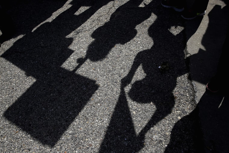 Demonstrators casts shadows as they gather outside the Holiday Inn Express in Janesville, Wis. on March 29, 2016. (Photo by Nam Y. Huh/AP)