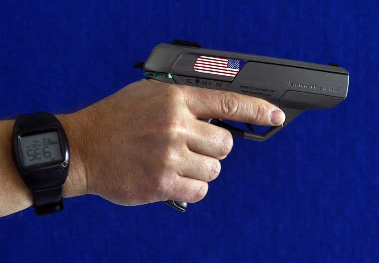 An employee holds a smart gun at the Armatix headquarters, May 14, 2014. The gun is implanted with a chip that allows it to be fired only if the shooter is wearing a watch that communicates with it through a radio signal. (Photo by Michael Dalder/Reuters)