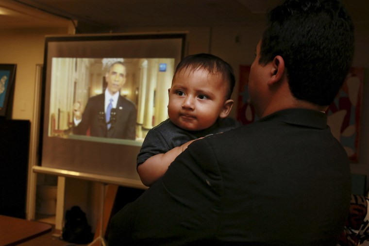 Christian Ramirez holds his nine-month old son Diego while watching President Barack Obama's White House speech on immigration at a viewing party at Alliance San Diego in San Diego, Calif., Nov. 20, 2014. (Photo by Sandy Huffaker/Reuters)