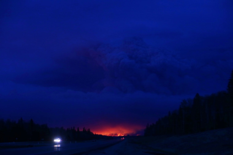 A plume of smoke hangs in the air as forest fires rage on in the distance in Fort McMurray, Alberta on May 4, 2016. (Photo by Cole Burston/AFP/Getty)