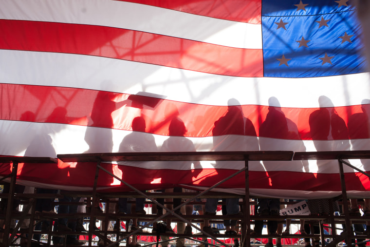 Supporters are seen backstage through an American flag during a Republican presidential candidate Donald Trump rally at the The Northwest Washington Fair and Event Center on May 7, 2016 in Lynden, Wash. (Photo by Matt Mills McKnight/Getty)